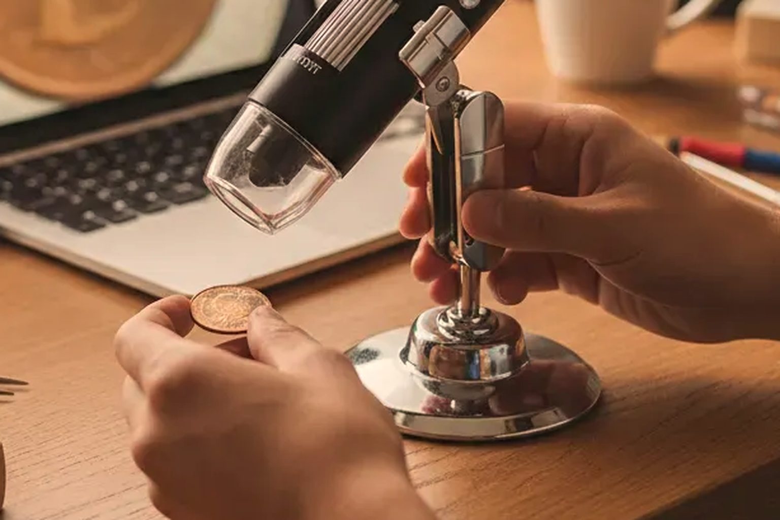Jiusion USB digital microscope with 8 LED light on its adjustable metal stand, positioned to inspect a coin.